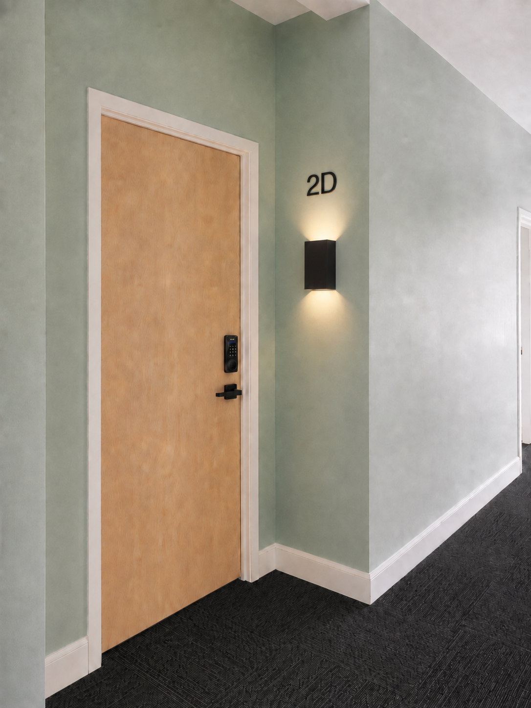 Apartment entry door with keypad lock, unit number and sconce lighting