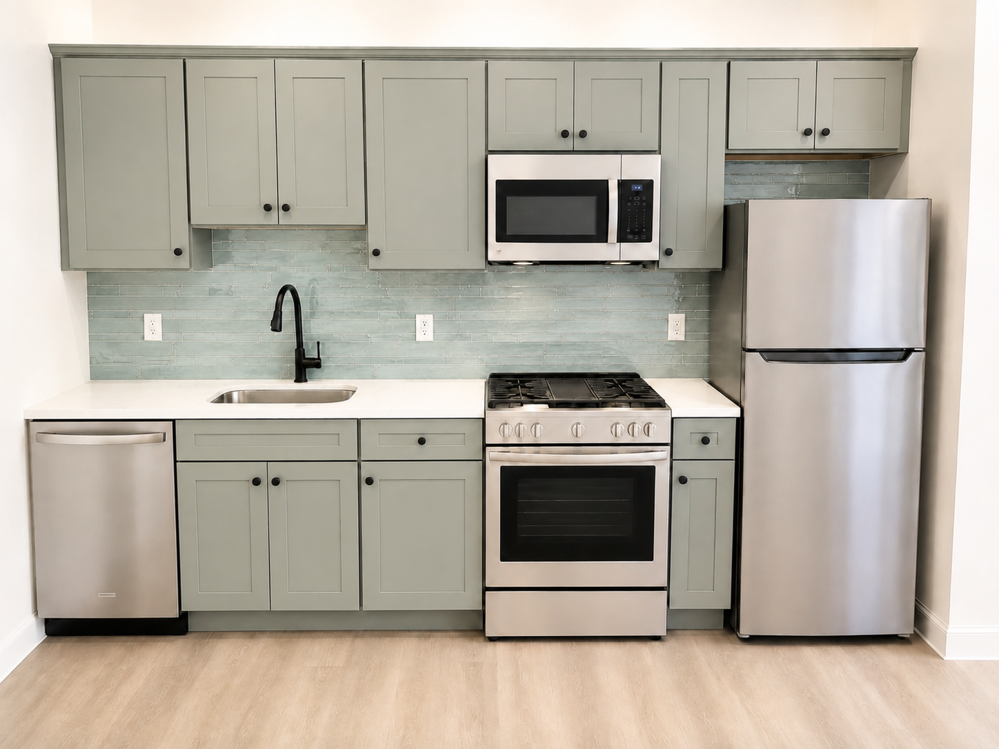 Apartment kitchen with sage green shaker cabinets, quartz countertops and stainless steel appliances
